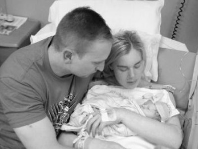 Mother and father holding infant in hospital bed