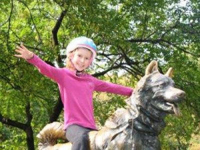 Girl wearing helmet, sitting on dog statue