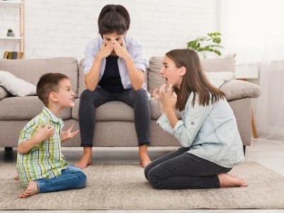 Children arguing in front of mom on couch