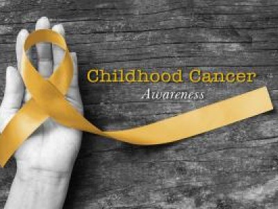 Hand holding gold ribbon representing Childhood Cancer