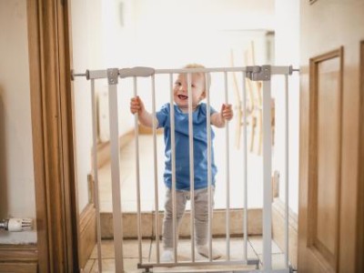 Toddler standing behind a baby gate