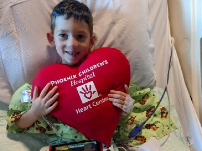 Young boy holding a large heart pillow to his chest