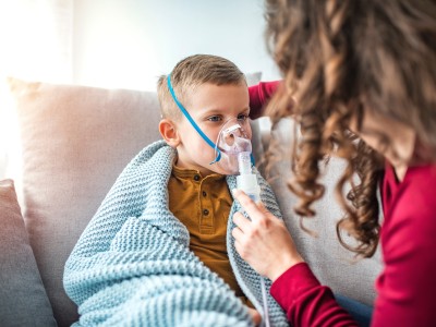 Child in blanket wearing a breathing treatment mask
