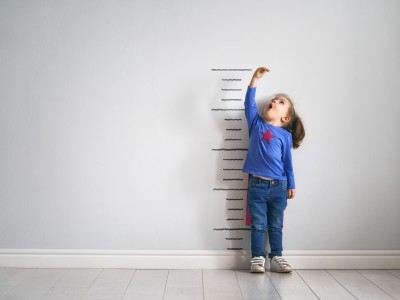 Child measuring self against ruler on wall