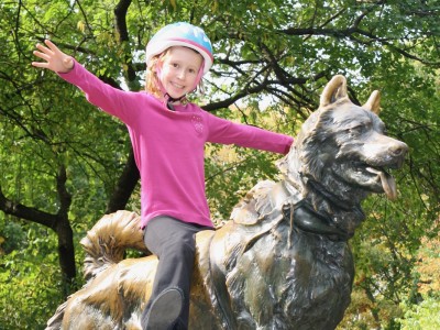 Girl wearing helmet, sitting on dog statue