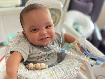 Baby in play seat, smiling at camera