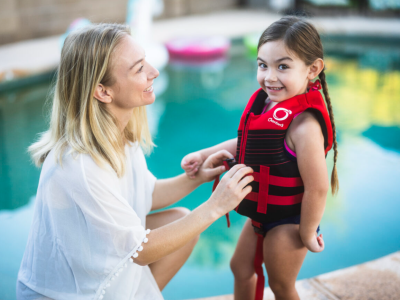 Woman and little girl in life jacket at pool