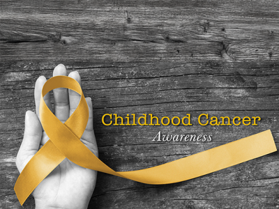 Hand holding gold ribbon representing Childhood Cancer