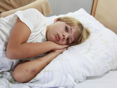 Sick child in bed with bruises on arms
