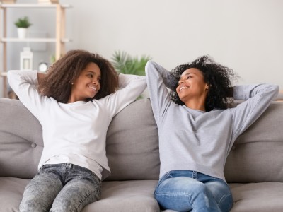 Mother and teen daughter relaxing on couch