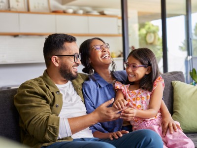Mom, dad and girl sitting on couch and smiling