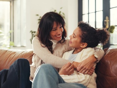 Mother hugging daughter on couch