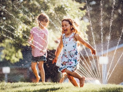 Children playing in yard sprinkler