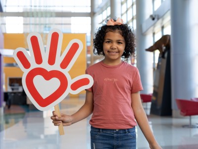 Girl in pink shirt, heart hand logo sign