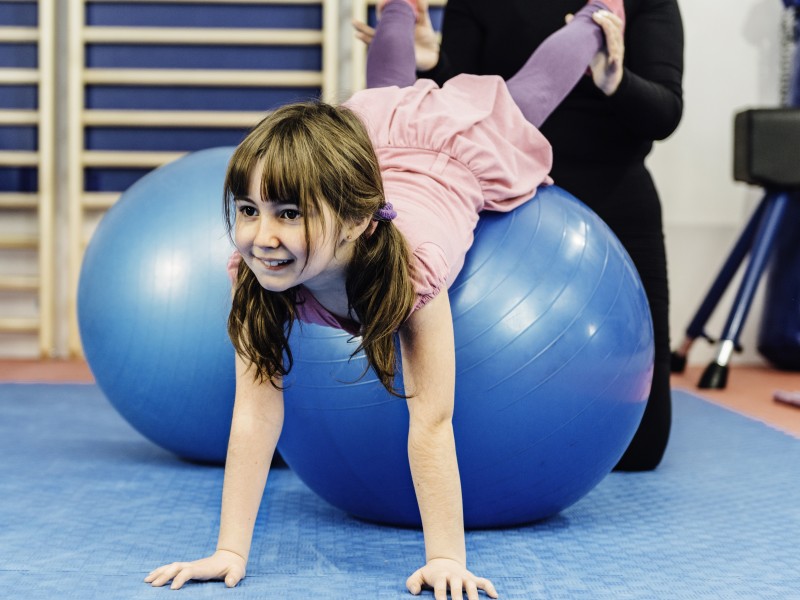 Little girl doing pelvic floor physical therapy on exercise ball