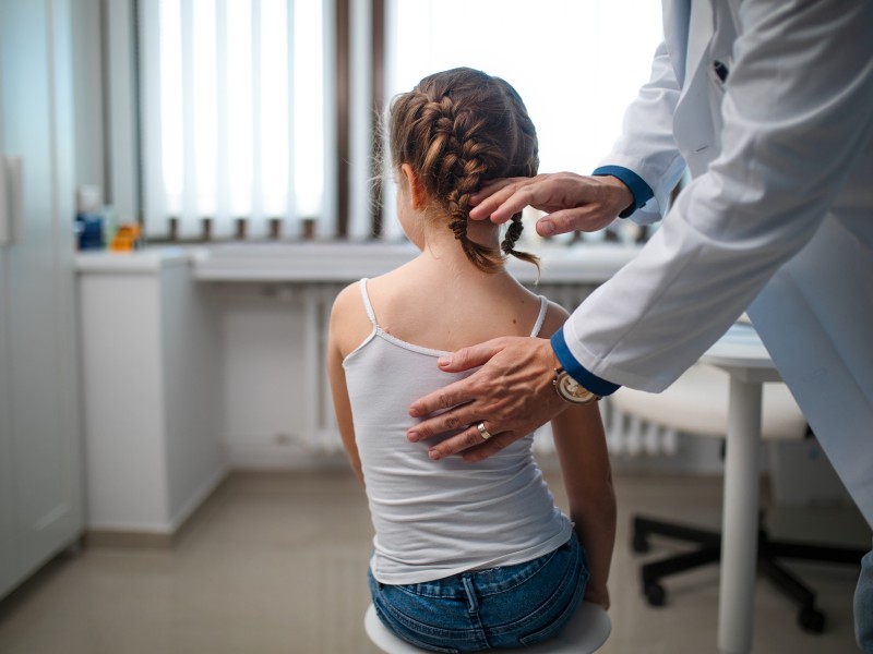 Child's back being checked by doctor