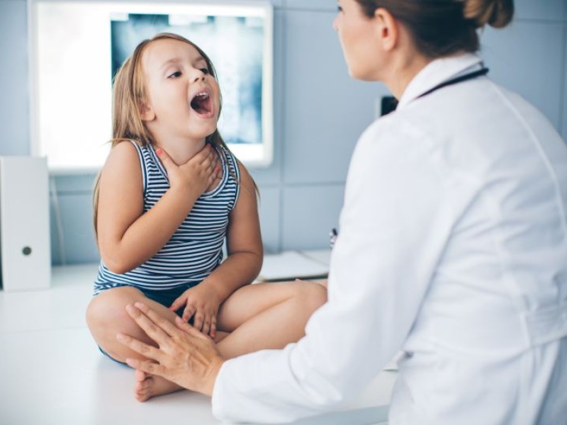 Doctor checking child's throat
