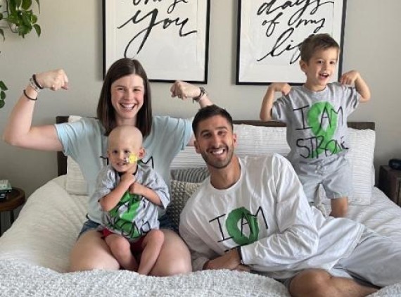Family of 4 on bed, flexing their muscles