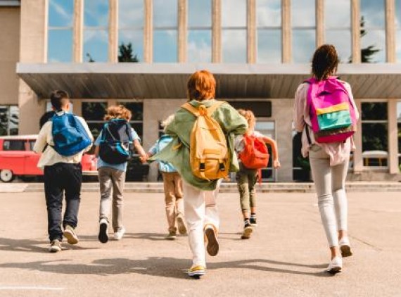 Kids wearing backpacks in front of school
