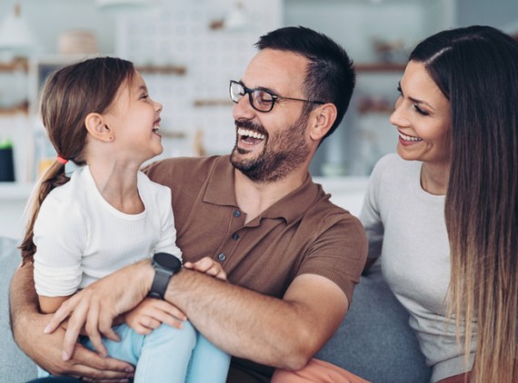 Mother, father and child sitting on couch, laughing