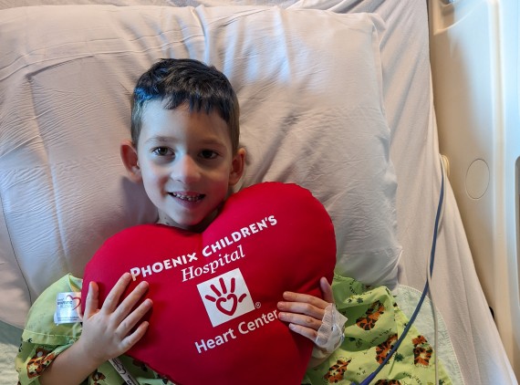 Young boy holding a large heart pillow to his chest