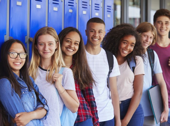 Group of smiling teens standing in front of lockers
