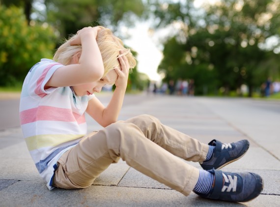 Young child on floor, holding his head