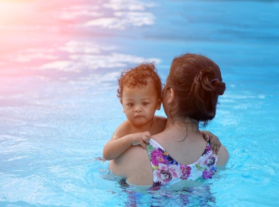 Mother holding infant in pool