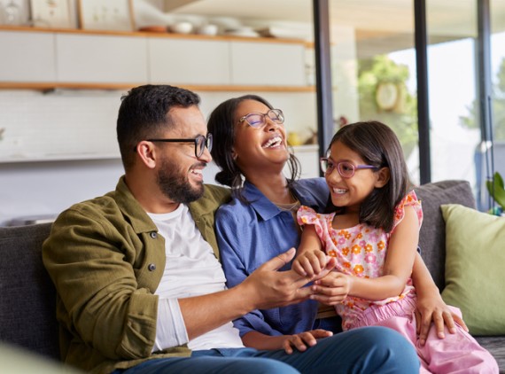 Mom, dad and girl sitting on couch and smiling