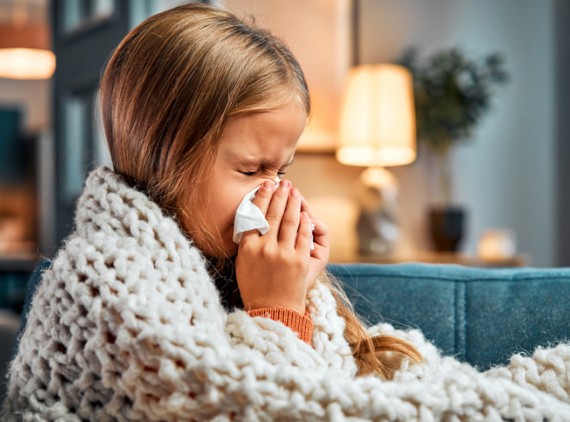 Young girl blowing her nose