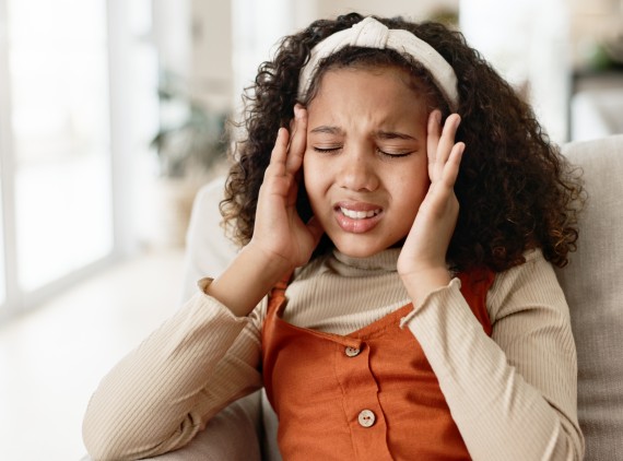 Adolescent girl pressing her temples in pain