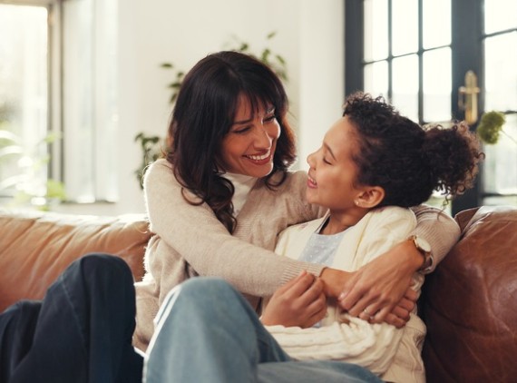 Mother hugging daughter on couch