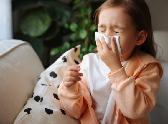 Toddler sneezing into tissue