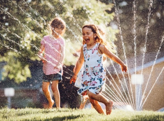 Children playing in yard sprinkler