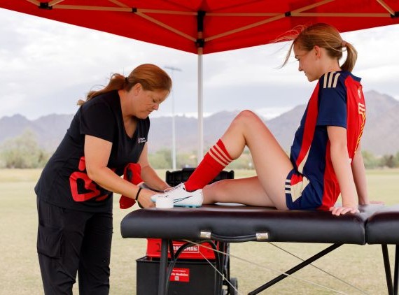 Teen athlete getting leg checked by medical professional