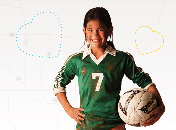 Girl in green uniform smiling and holding soccer ball