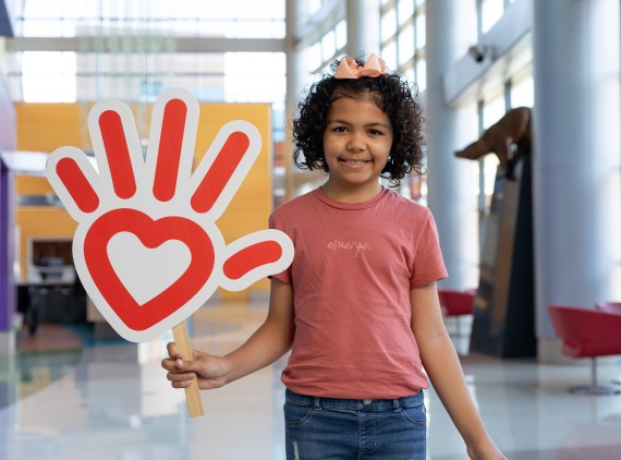 Girl in pink shirt, heart hand logo sign
