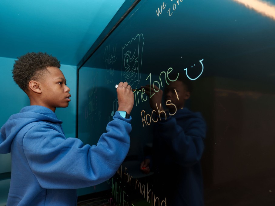 Boy writing on whiteboard in The Zone