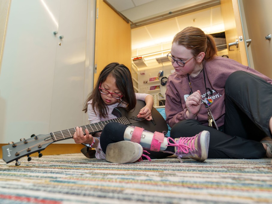 Woman teaching girl to play the guitar in The Zone