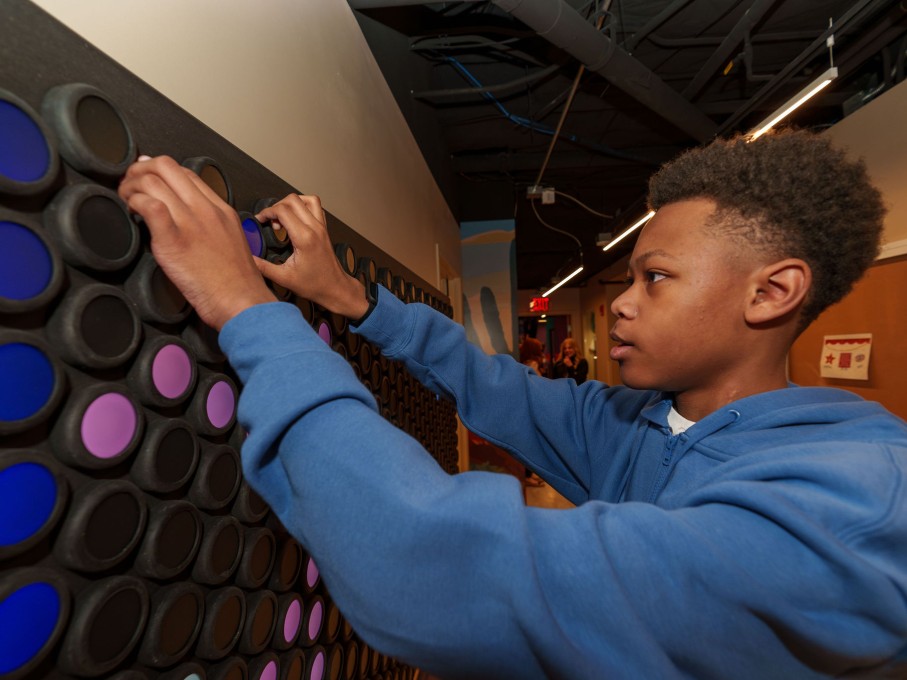 Boy playing with Lite-Brite wall in The Zone