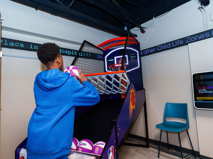 Boy playing basketball arcade game in The Zone