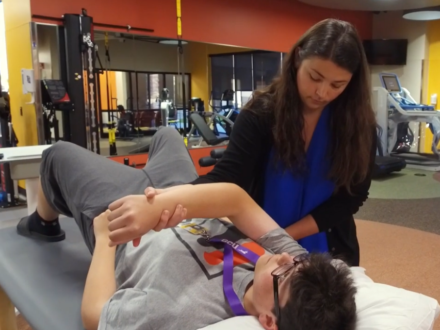 Teenager and physical therapist at sports PT gym