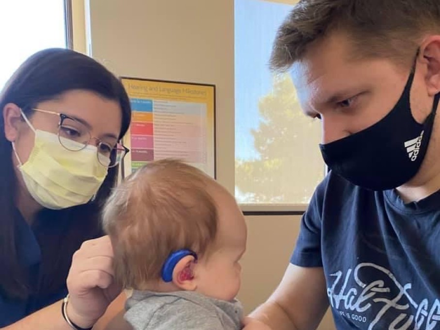 Provider adjusting hearing aids on infant