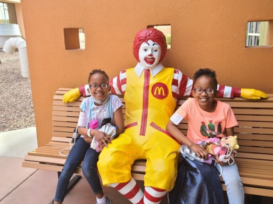 Twin girls on bench with Ronald McDonald statue
