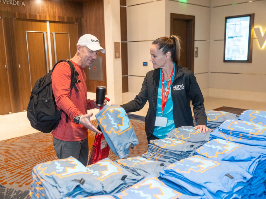 Woman handing man a blue EMS shirt at conference