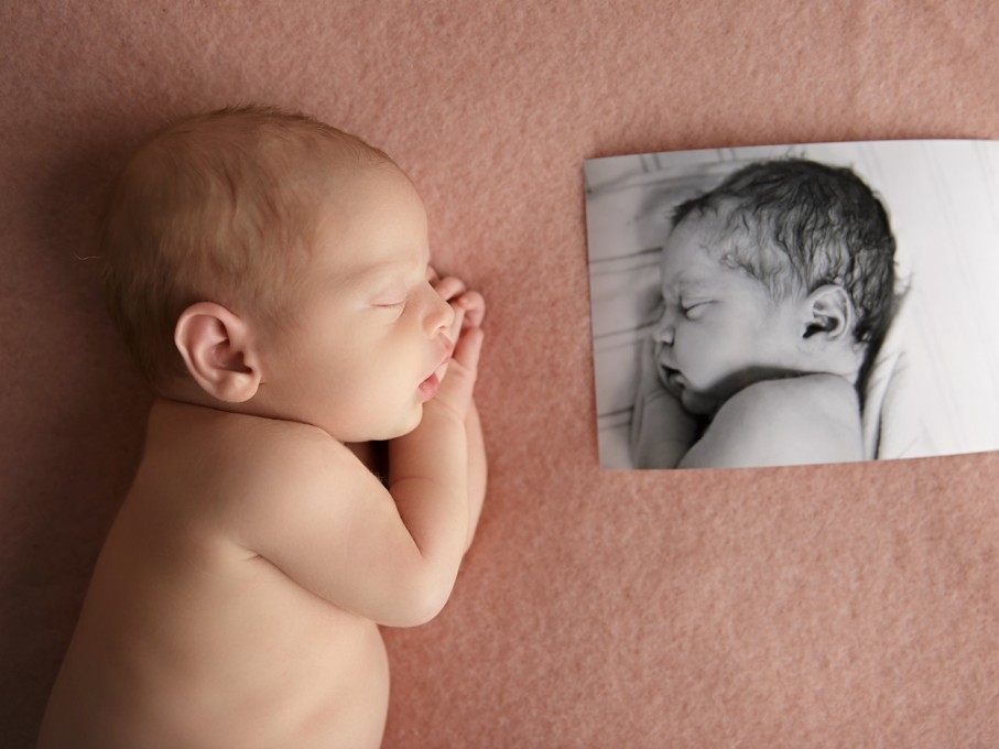 Sleeping infant posing with photo of twin