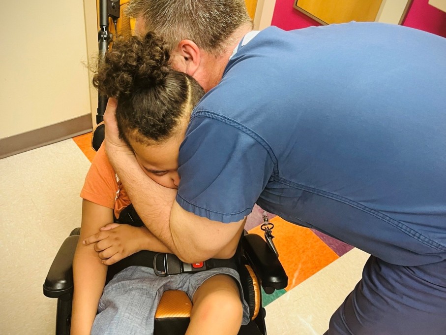 Provider hugging patient in wheelchair