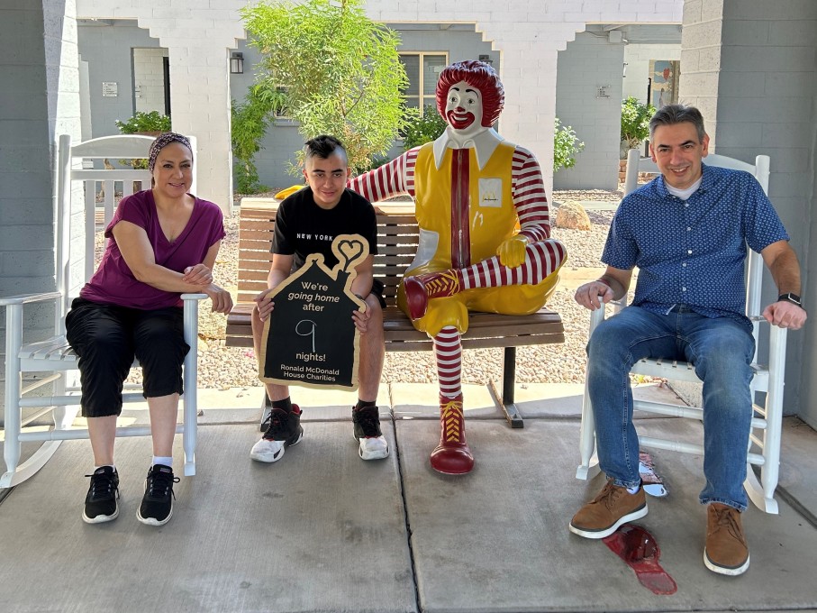 Teen boy and parents posing with Ronald McDonald statue
