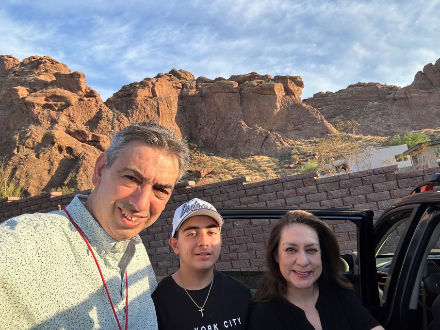 Teen boy and parents smiling in front of mountains