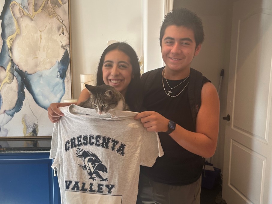 Teen boy and girl smiling while holding cat and t-shirt